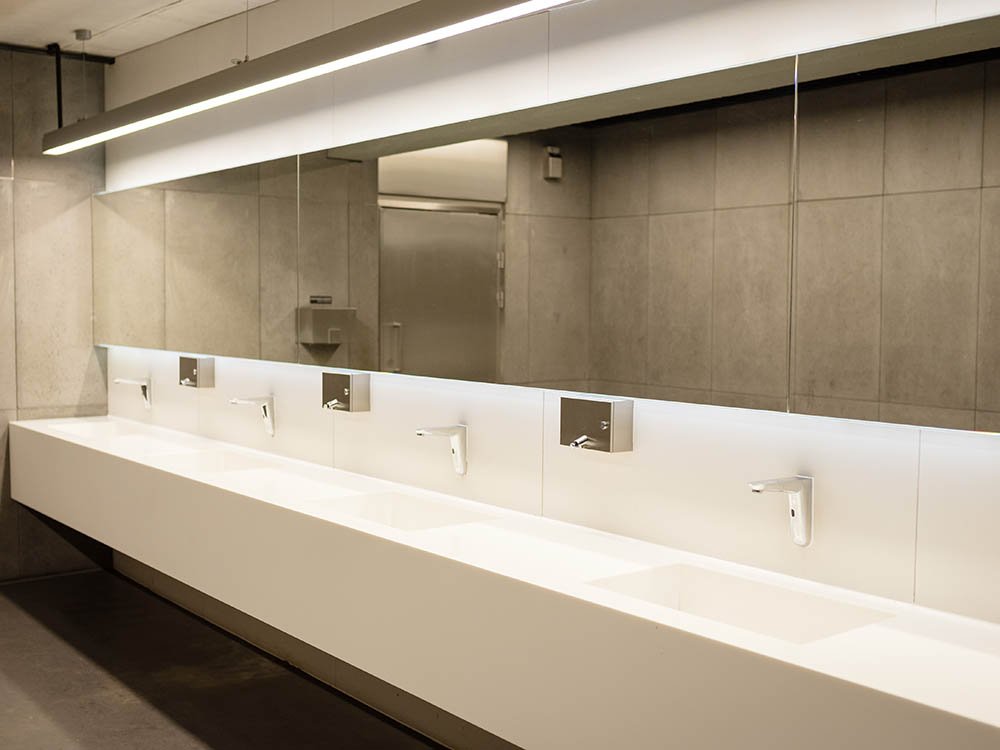 Hygienischer Waschplatz mit Sensorarmaturen in modernem öffentlichen Sanitärraum Waschbereich mit berührungslosen Armaturen und moderner Spiegelwand in öffentlicher Sanitäreinrichtung