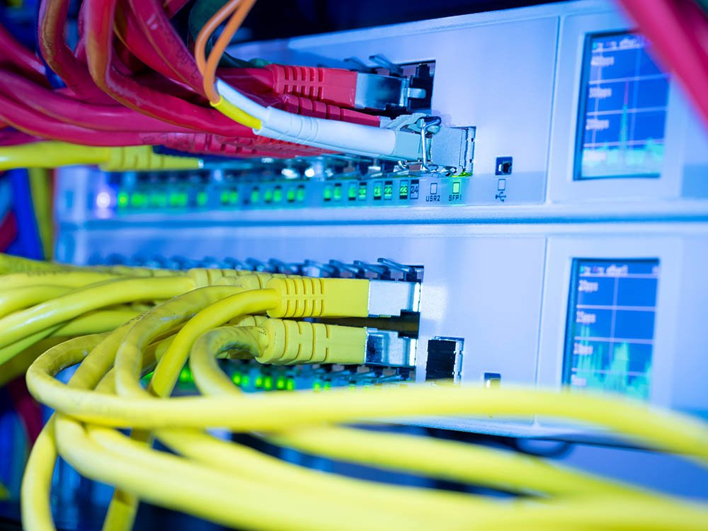 Daten- und Netzwerktechnik für moderne Elektroinstallationen in Gebäuden Netzwerk-Switch mit eingesteckten Ethernet-Kabeln in strukturierter Gebäudeverkabelung